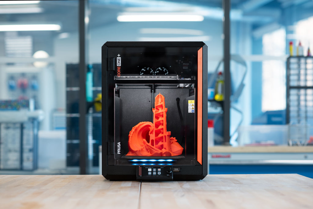 CORE One+ (Gen 2) printing an orange model in a workshop