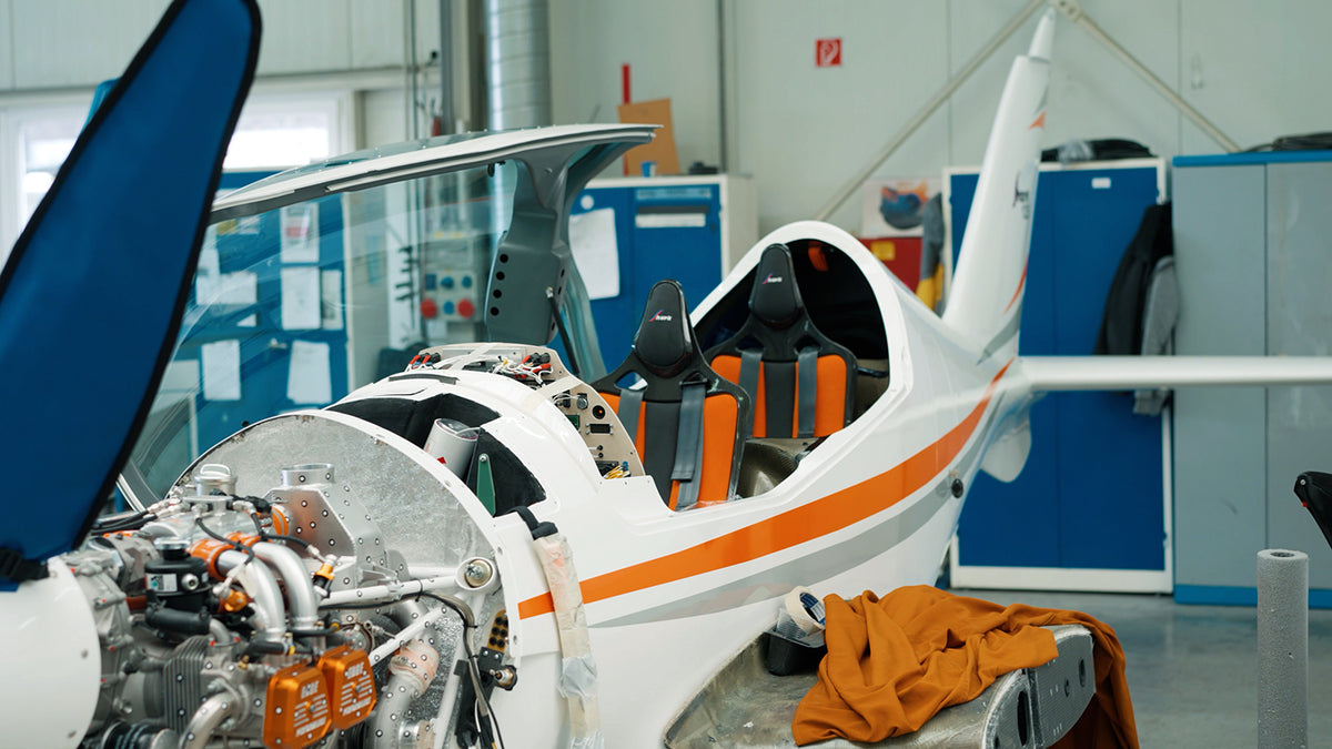 Original Prusa 3D printer beside a light aircraft in an aviation hangar
